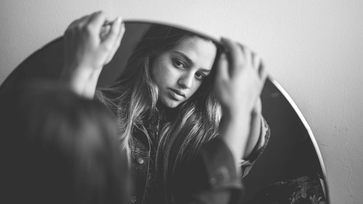 Elegant black and white portrait of a woman reflecting in a mirror.
